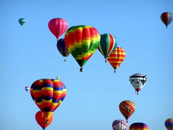 Colorful hot air balloons floating in a clear blue sky, showcasing a vibrant festival scene.